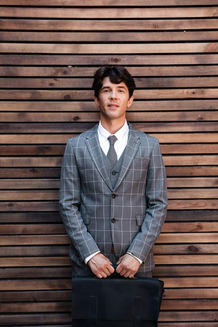 handsome-businessman-suit-standing-with-briefcase-against-wooden-wall_171337-8366